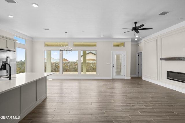13375 Jeff Winton Dr, El Paso, TX 79928 - unfurnished living room featuring dark wood-type flooring, recessed lighting, a glass covered fireplace, a ceiling fan, and a chandelier