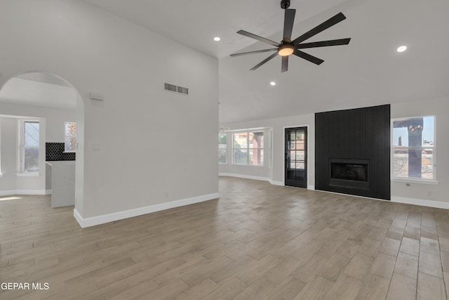 4321 Loma Casitas Rd, El Paso, TX 79934 - unfurnished living room with high vaulted ceiling, ceiling fan, arched walkways, light wood-style floors, and a large fireplace