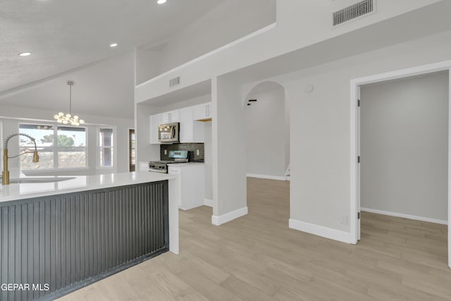 4321 Loma Casitas Rd, El Paso, TX 79934 - kitchen with stainless steel appliances, white cabinetry, arched walkways, light wood-style floors, and recessed lighting