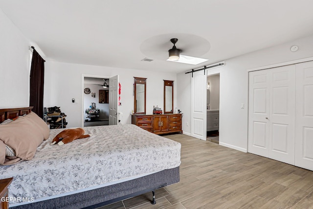 9128 Diana Dr, El Paso, TX 79924 - bedroom with a barn door, light wood-style flooring, ceiling fan, ensuite bathroom, and a closet