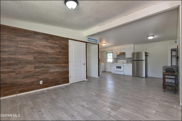 5726 Dearborne Dr, El Paso, TX 79924 - unfurnished living room with wood walls, a textured ceiling, and light wood-type flooring