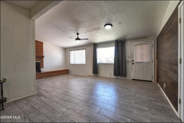 5726 Dearborne Dr, El Paso, TX 79924 - unfurnished living room with a ceiling fan, a textured ceiling, a fireplace, and wood tiled floors