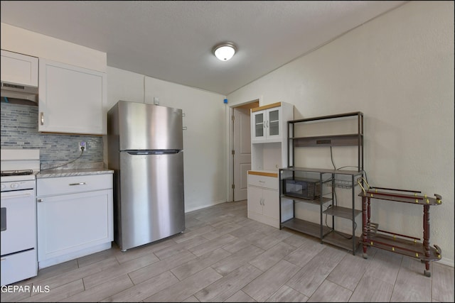 5726 Dearborne Dr, El Paso, TX 79924 - kitchen with freestanding refrigerator, under cabinet range hood, white gas stove, decorative backsplash, and wood tiled floors