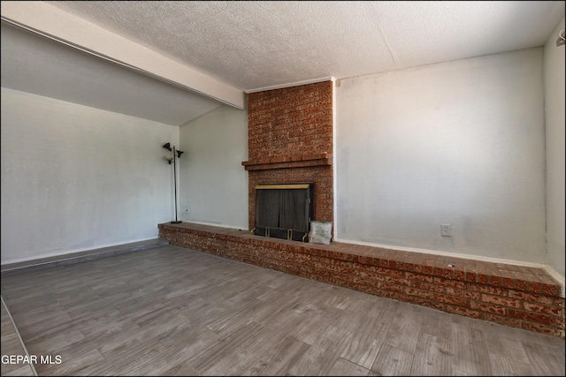 5726 Dearborne Dr, El Paso, TX 79924 - unfurnished living room with wood finished floors, a fireplace, and a textured ceiling
