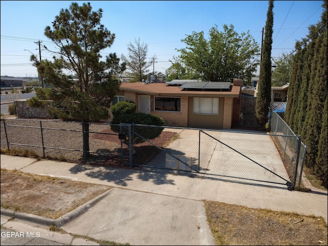 5726 Dearborne Dr, El Paso, TX 79924 - view of front of home featuring a fenced front yard, roof mounted solar panels, brick siding, a gate, and a chimney