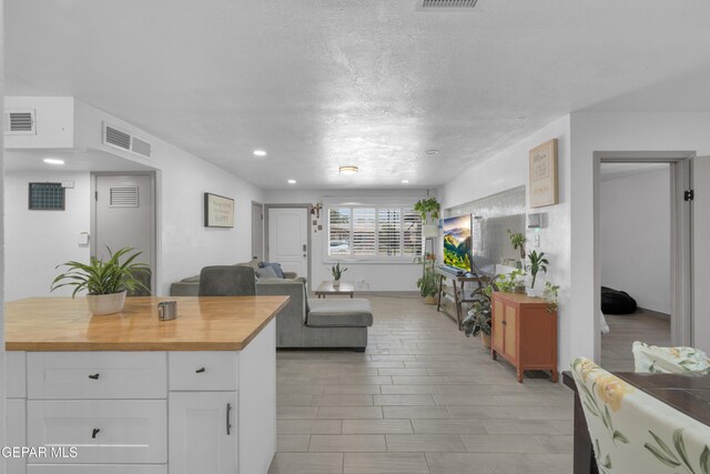 8142 Cook Dr, El Paso, TX 79907 - kitchen featuring wood counters, white cabinets, open floor plan, a textured ceiling, and recessed lighting
