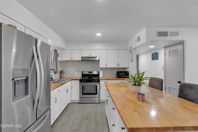 8142 Cook Dr, El Paso, TX 79907 - kitchen with appliances with stainless steel finishes, wood counters, under cabinet range hood, white cabinets, and recessed lighting
