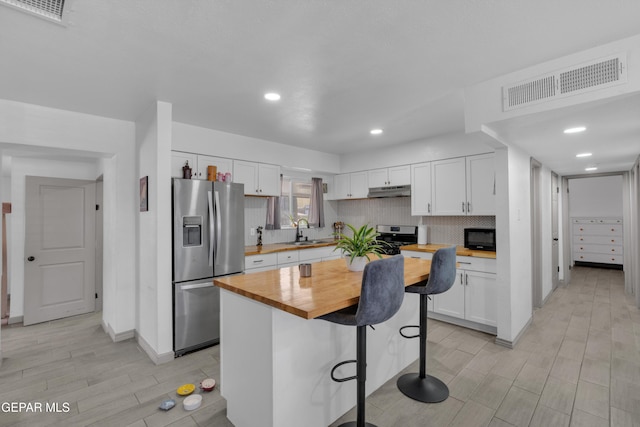 8142 Cook Dr, El Paso, TX 79907 - kitchen featuring stainless steel fridge, butcher block countertops, white cabinetry, black microwave, and wood finish floors