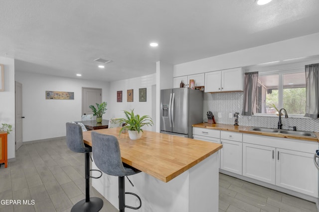 8142 Cook Dr, El Paso, TX 79907 - kitchen with wooden counters, stainless steel refrigerator with ice dispenser, backsplash, white cabinets, and a kitchen breakfast bar