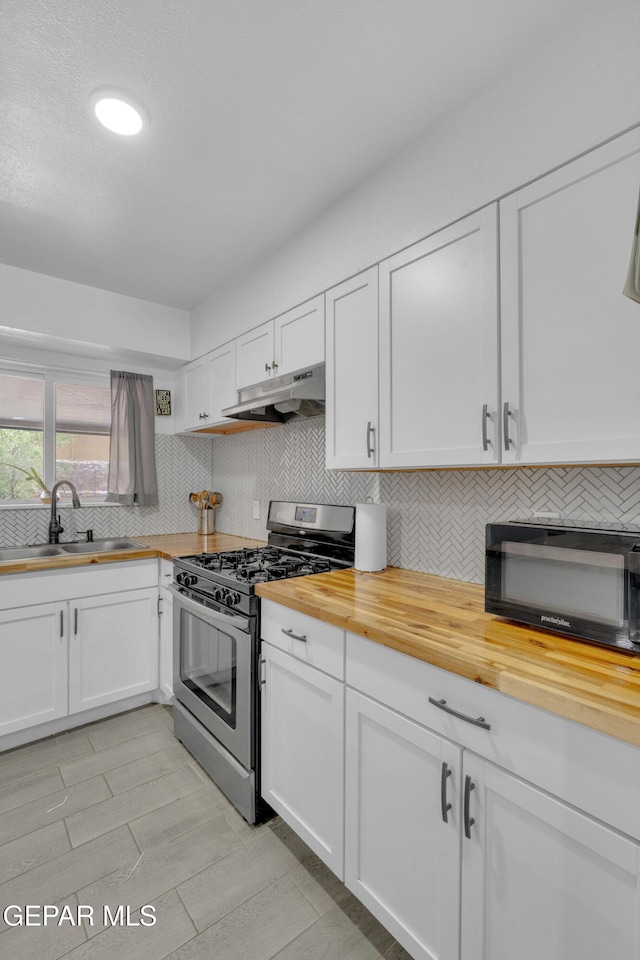 8142 Cook Dr, El Paso, TX 79907 - kitchen with wood counters, stainless steel gas range, under cabinet range hood, black microwave, and white cabinetry