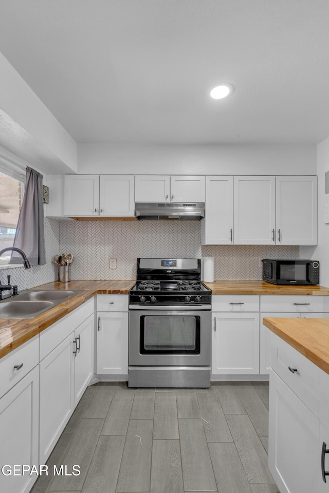 8142 Cook Dr, El Paso, TX 79907 - kitchen featuring gas range, butcher block countertops, under cabinet range hood, black microwave, and white cabinets