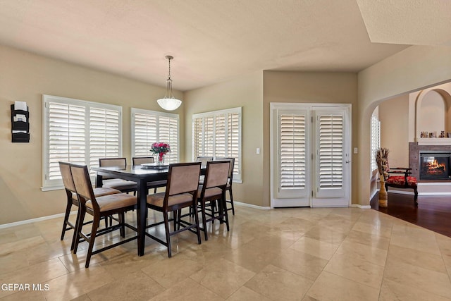 6310 Franklin Crest Dr, El Paso, TX 79912 - dining space featuring a glass covered fireplace, arched walkways, and a textured ceiling
