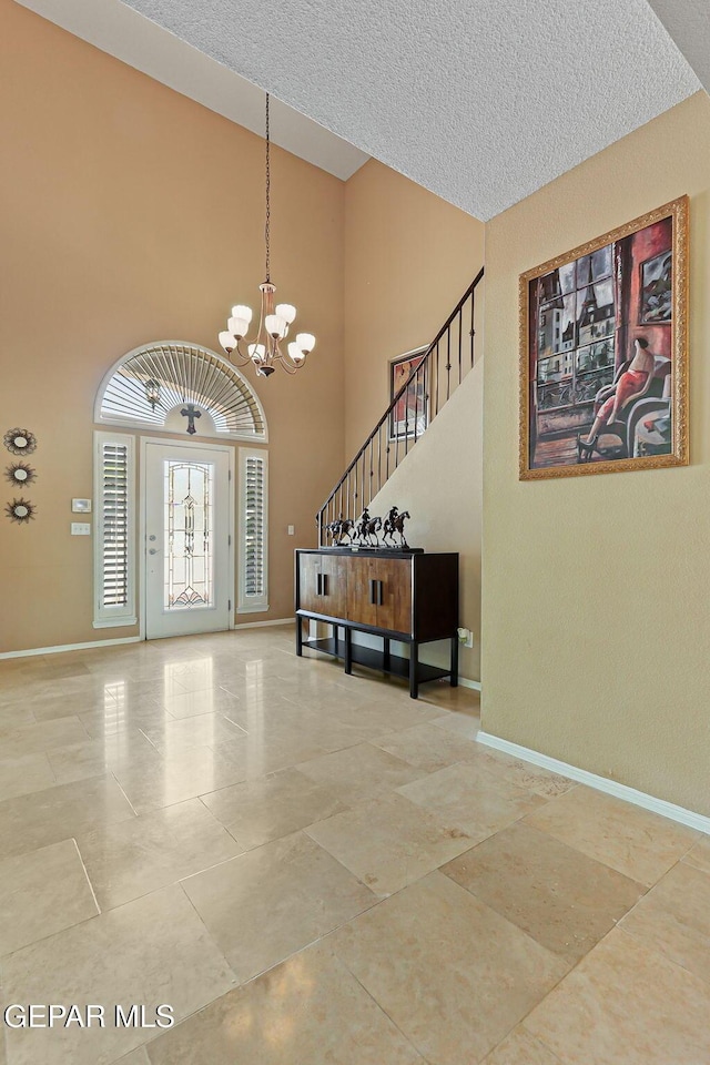 6310 Franklin Crest Dr, El Paso, TX 79912 - entrance foyer with a chandelier, a high ceiling, tile patterned floors, a textured ceiling, and stairway