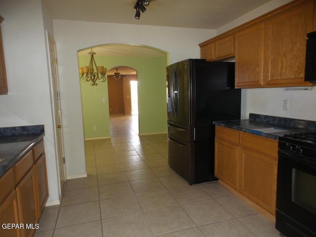 3204 Olive Point Dr, El Paso, TX 79938 - kitchen with arched walkways, black appliances, light tile patterned flooring, a chandelier, and brown cabinetry