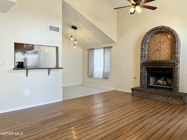 11713 Francis Scobee Dr, El Paso, TX 79936 - unfurnished living room with light wood-style flooring, a high ceiling, a ceiling fan, and a fireplace