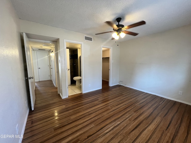11713 Francis Scobee Dr, El Paso, TX 79936 - unfurnished bedroom featuring wood finished floors, a walk in closet, a textured ceiling, a closet, and ensuite bath