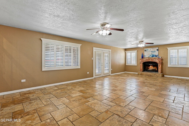 796 Fescue Dr, Canutillo, TX 79835 - unfurnished living room featuring ceiling fan, a textured ceiling, a lit fireplace, and stone tile floors