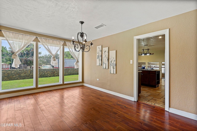 796 Fescue Dr, Canutillo, TX 79835 - unfurnished dining area featuring a chandelier, dark wood-style floors, and a textured wall