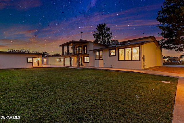 796 Fescue Dr, Canutillo, TX 79835 - back of property at dusk featuring a balcony, a patio area, a yard, and stucco siding