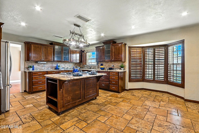 796 Fescue Dr, Canutillo, TX 79835 - kitchen with tasteful backsplash, recessed lighting, dark brown cabinets, a kitchen island, and a textured ceiling