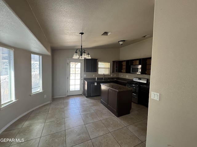 14325 Woods Point Ave, El Paso, TX 79938 - kitchen with black gas stove, stainless steel microwave, a center island, a chandelier, and light tile patterned flooring