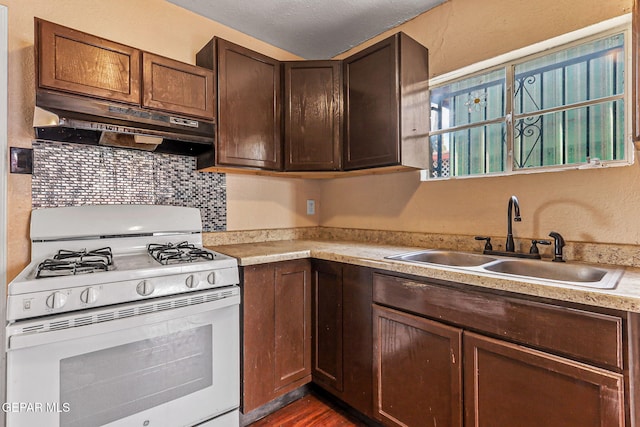 541 Val Verde St, El Paso, TX 79905 - kitchen with white range with gas cooktop, under cabinet range hood, light countertops, decorative backsplash, and dark wood-type flooring