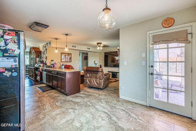 7366 Luz De Dia Ct, El Paso, TX 79912 - kitchen with freestanding refrigerator, dark brown cabinets, open floor plan, hanging light fixtures, and a ceiling fan