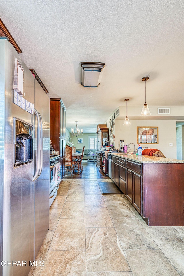 7366 Luz De Dia Ct, El Paso, TX 79912 - kitchen with appliances with stainless steel finishes, a textured ceiling, hanging light fixtures, light stone countertops, and dark brown cabinets