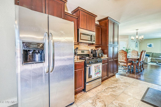 7366 Luz De Dia Ct, El Paso, TX 79912 - kitchen featuring stainless steel appliances, a chandelier, open floor plan, tasteful backsplash, and light stone countertops