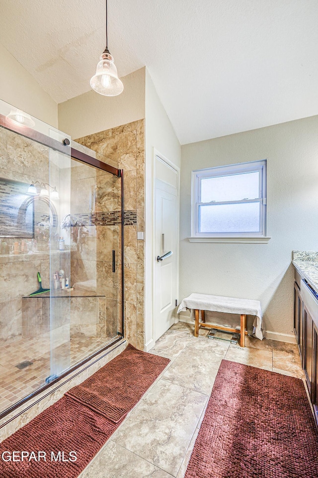 7366 Luz De Dia Ct, El Paso, TX 79912 - bathroom with vaulted ceiling, a stall shower, vanity, and a textured ceiling