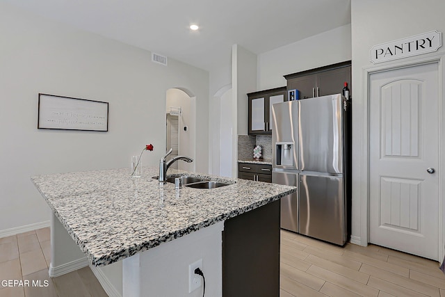 13860 Paseo Sereno Dr, El Paso, TX 79928 - kitchen with stainless steel refrigerator with ice dispenser, arched walkways, light stone counters, wood tiled floors, and a center island with sink