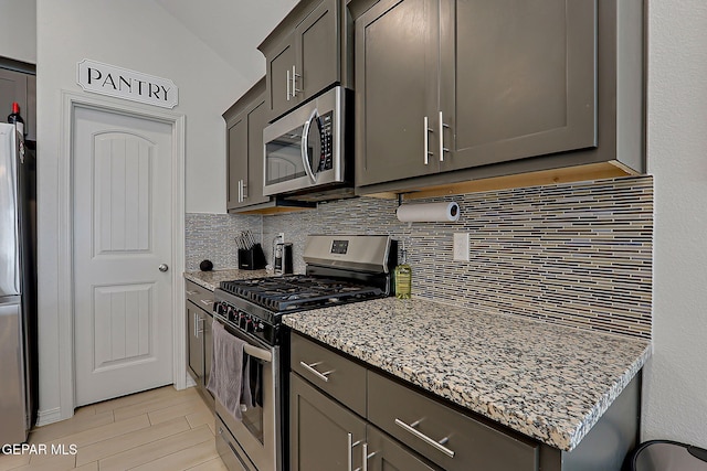 13860 Paseo Sereno Dr, El Paso, TX 79928 - kitchen with stainless steel appliances, tasteful backsplash, light stone countertops, lofted ceiling, and light wood-style floors
