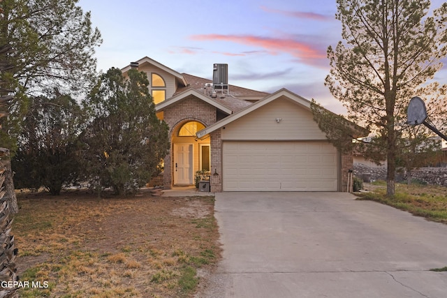 5713 Saplinas Rd, El Paso, TX 79932 - view of front of home with brick siding, driveway, a garage, and roof with shingles