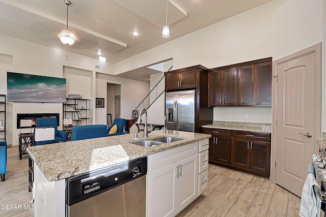 7825 Enchanted View Dr, El Paso, TX 79911 - kitchen with appliances with stainless steel finishes, dark brown cabinets, white cabinetry, a kitchen island with sink, and light stone counters