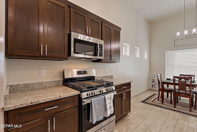 7825 Enchanted View Dr, El Paso, TX 79911 - kitchen with appliances with stainless steel finishes, dark brown cabinetry, pendant lighting, light wood-style floors, and light stone countertops