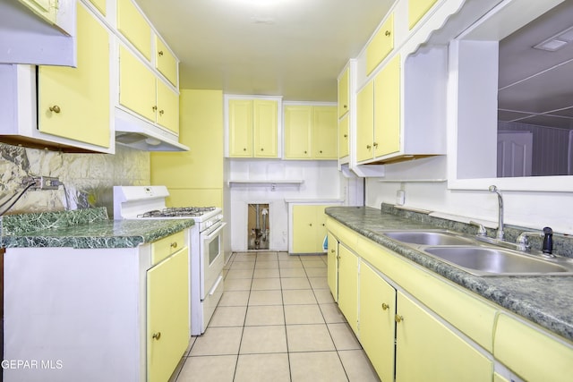 1268 Stanley St, El Paso, TX 79907 - kitchen with white gas stove, under cabinet range hood, light tile patterned flooring, tasteful backsplash, and dark countertops