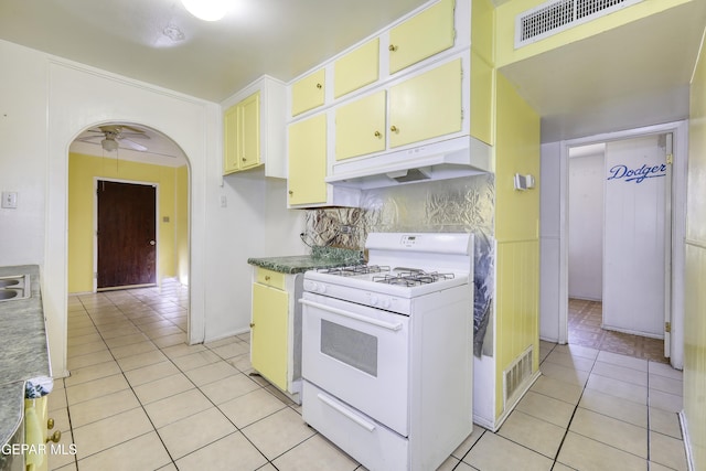 1268 Stanley St, El Paso, TX 79907 - kitchen featuring white range with gas stovetop, under cabinet range hood, light tile patterned floors, ceiling fan, and backsplash