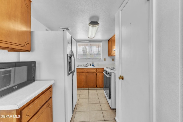 8763 Cathedral Cir, El Paso, TX 79907 - kitchen featuring white appliances, a textured ceiling, brown cabinetry, light tile patterned flooring, and light countertops