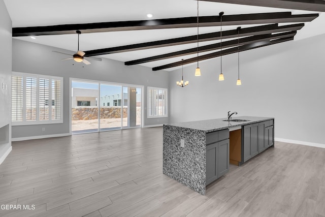 13829 Summer View Ave, Horizon City, TX 79928 - kitchen with gray cabinets, open floor plan, a ceiling fan, beam ceiling, and light stone counters