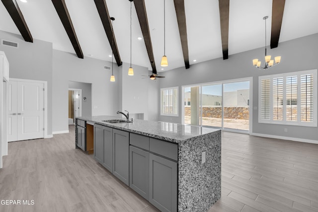 13829 Summer View Ave, Horizon City, TX 79928 - kitchen featuring gray cabinetry, open floor plan, beam ceiling, a center island with sink, and a chandelier
