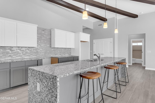 13829 Summer View Ave, Horizon City, TX 79928 - kitchen featuring light stone countertops, tasteful backsplash, beam ceiling, a high ceiling, and gray cabinetry