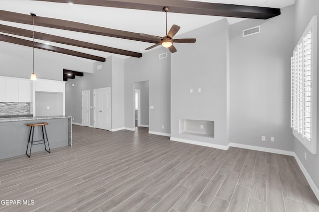 13829 Summer View Ave, Horizon City, TX 79928 - unfurnished living room with beamed ceiling, ceiling fan, healthy amount of natural light, high vaulted ceiling, and light wood finished floors