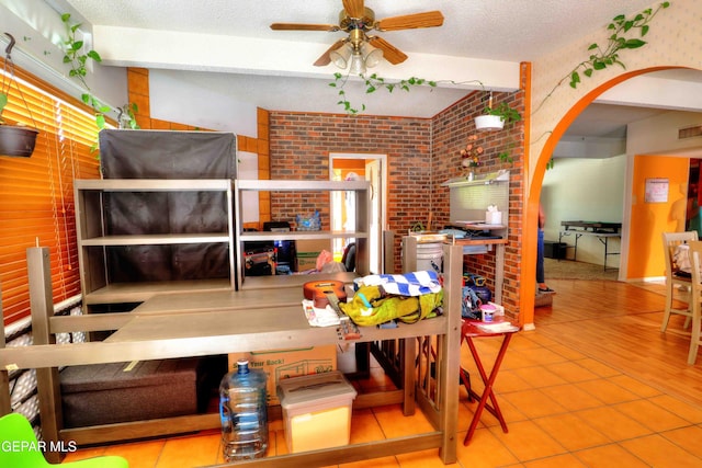 5108 Paris Ave, El Paso, TX 79924 - dining room with ceiling fan, brick wall, arched walkways, tile patterned floors, and a textured ceiling