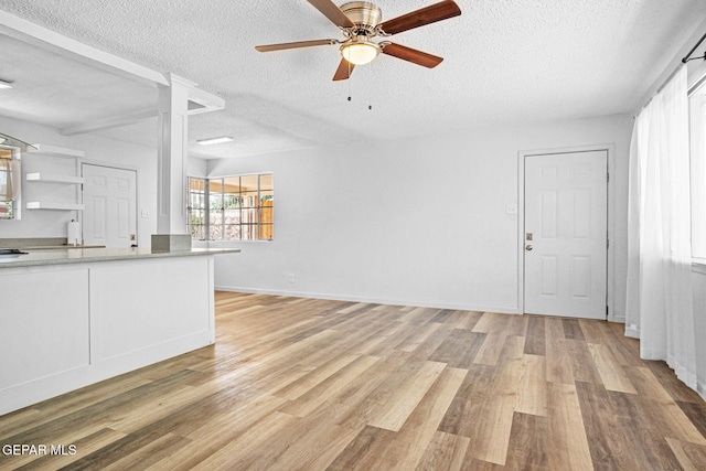 1400 Elmhurst Dr, El Paso, TX 79925 - unfurnished living room with a textured ceiling, light wood-type flooring, a ceiling fan, and ornate columns