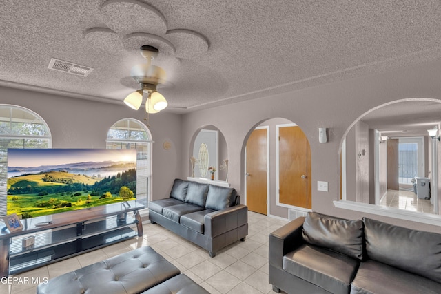 tiled living room featuring ceiling fan, arched walkways, and a textured ceiling