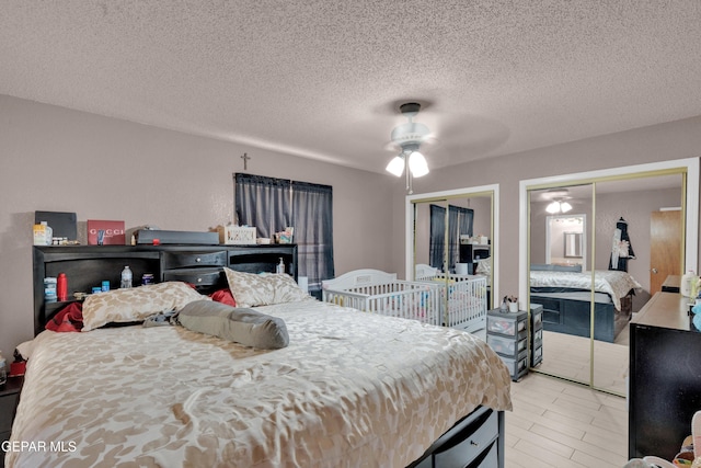 bedroom with two closets, a textured ceiling, and a ceiling fan