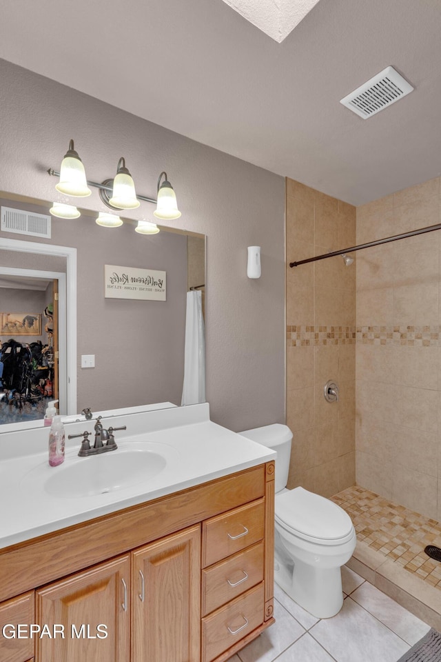 full bathroom with tile patterned floors, vanity, and a tile shower