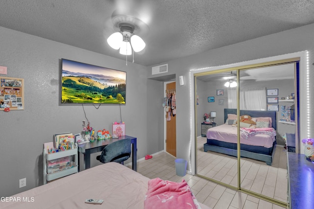 bedroom with a textured ceiling, a textured wall, a closet, and ceiling fan