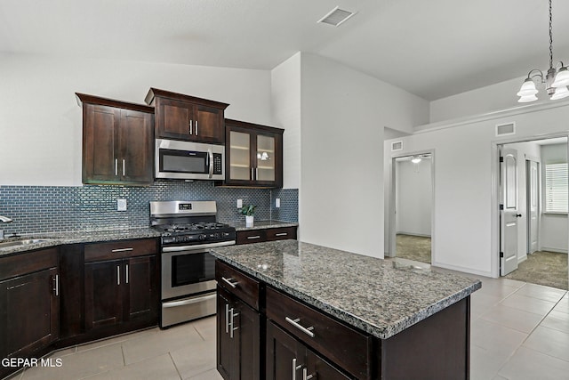 12469 Lanchester Dr, El Paso, TX 79928 - kitchen with stainless steel appliances, backsplash, light tile patterned flooring, dark stone counters, and a chandelier