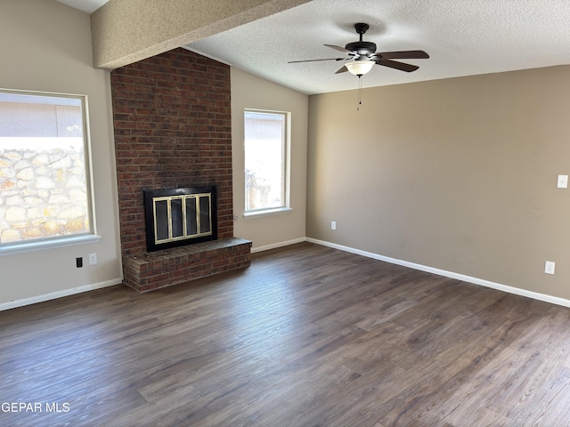 378 Hourglass Dr, El Paso, TX 79915 - unfurnished living room featuring a ceiling fan, a brick fireplace, lofted ceiling, dark wood-style flooring, and a textured ceiling